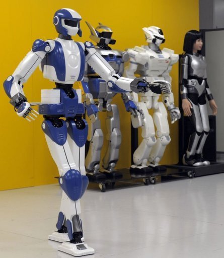 Robot HRP-4 spaceruje przy swoich poprzednich wersjach na konferencji w Tsakuba w Japonii.